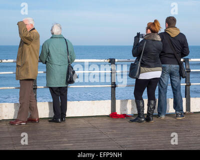 Due coppie, giovani e vecchi, sulla fine del Saltburn pier godendo della vista nel caldo sole invernale Foto Stock