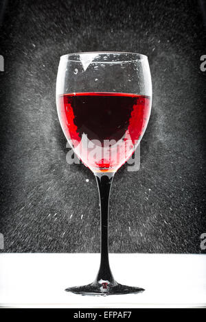 Vetro con vino rosso. Gli spruzzi d'acqua Foto Stock