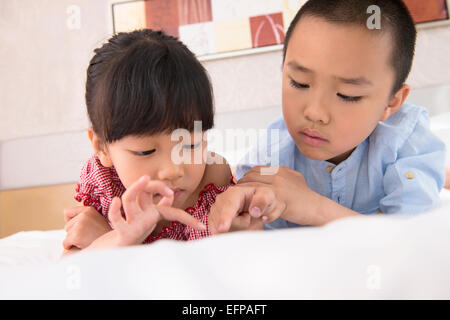 Un ragazzo e una ragazza utilizzando tablet a letto Foto Stock