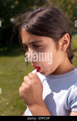 Bambino felice giovane ragazza al di fuori di aspirare lollipop dolce su una maniglia di carta necessario guardare dopo denti a causa di zucchero Foto Stock
