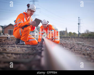 Manutenzione ferroviaria lavoratori con tavoletta digitale per ispezionare la via Foto Stock