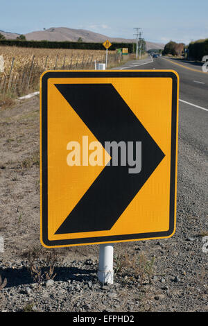 Avviso di sicurezza con freccette su un territorio rurale Nuova Zelanda road che indica una curva in strada Foto Stock