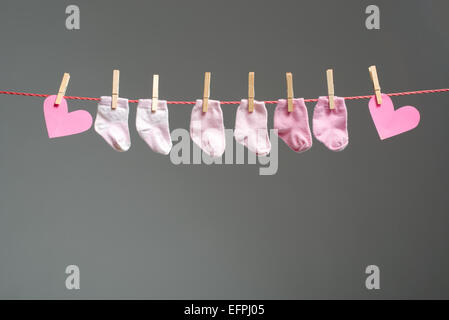 Baby girl calzini e cuore della carta sul stendibiancheria Foto Stock