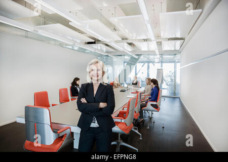 Donna matura in ufficio con i colleghi in background Foto Stock