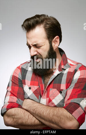 Ritratto in studio di angosciosa barbuto giovane con le braccia incrociate Foto Stock