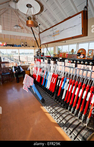 Il segnalatore a Williton stazione sul West Somerset Railway tra trainsin la sua casella segnale Foto Stock