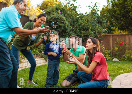 Tre generazioni la famiglia soffiare bolle in giardino Foto Stock