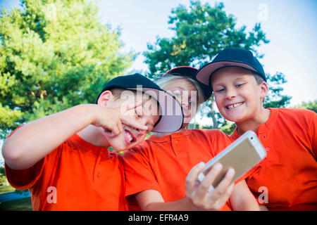 I giovani giocatori di baseball tenendo autoritratto utilizza lo smartphone Foto Stock