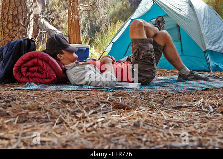 Giovane maschio camper in appoggio in foresta, Los Angeles, California, Stati Uniti d'America Foto Stock