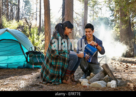 Coppia giovane versando il caffè da falò in foresta, Los Angeles, California, Stati Uniti d'America Foto Stock