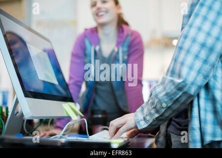 Due persone a un computer repair shop, una digitazione e controllo di un monitor. Foto Stock