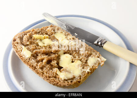 Fetta di pane appena sfornato caldo Pane integrale con burro su una piastra con il coltello Foto Stock