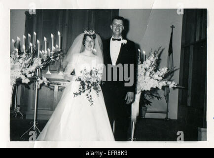 In Canada. 12 dic 2014. CIRCA degli anni cinquanta: Riproduzione di un antico foto mostra la sposa e lo sposo in posa nella chiesa, la sposa tenendo un bouquet, su un candelabro candele accese © Igor Golovniov/ZUMA filo/ZUMAPRESS.com/Alamy Live News Foto Stock