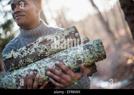 Uomo che porta legna da ardere nella foresta in autunno. Foto Stock