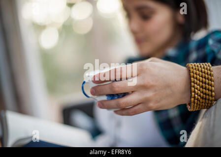In prossimità di una donna di mano che regge una tazza di tè, indossando un bracciale. Foto Stock