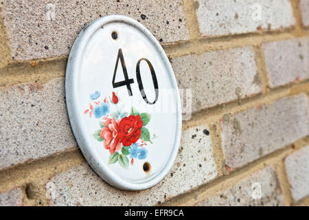 Il numero 40 su un piatto di portata in ceramica bianca con disegno floreale, attaccato al muro di mattoni di una casa a significare indirizzo Foto Stock