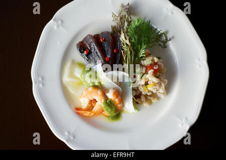 Piastra con varietà di frutti di mare e di orzo con Affettato vegetale ed erbe aromatiche Foto Stock