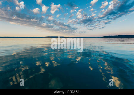 Nuvole drammatico e cielo riflettendo su calme acque dell'oceano al tramonto, cappa Canal canale d'acqua nei pressi di Puget Sound. Foto Stock