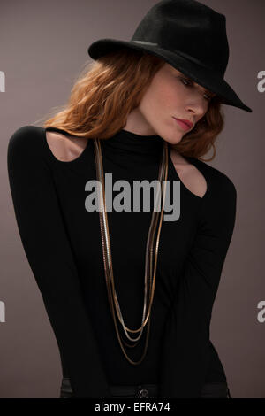 Donna con red capelli ricci indossando un cappello nero Foto Stock