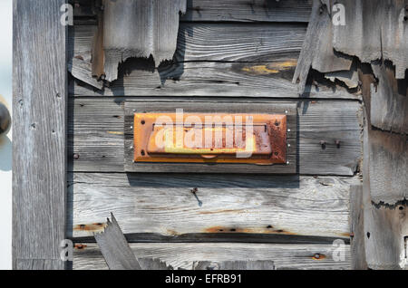 Rusty mailbox sul legname stagionato parete del vecchio edificio Foto Stock