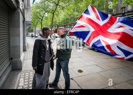 Brustchom Ziamani (L) qui raffigurato il 9 maggio 2014 fuori della Commissione indiana di Londra che è confrontata con Paul Golding (R) del primo movimento nazionalista britannico. Brustchom Ziamani, 19 anni, è stato rimandato in custodia dopo essere comparso in tribunale per affrontare accuse di terrore. Ziamani, di Camberwell, a sud-est di Londra, è stato accusato di 'intraprendere una condotta in preparazione di atti terroristici' il 19 agosto 2014 o prima. Il signor Ziamani è stato arrestato martedì 19 agosto 2014 nella zona est di Londra. Attualmente è in fase di processo presso l'Old Bailey Court. Foto Stock