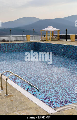 Svuotare la piscina con piastrelle blu in autunno il giorno Foto Stock