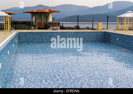 Svuotare la piscina con piastrelle blu in autunno il giorno Foto Stock