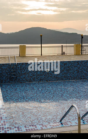 Svuotare la piscina con piastrelle blu in autunno il giorno Foto Stock