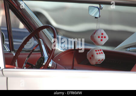 Interno lato conducente di vintage classic car, con dadi fuzzy appeso lo specchio retrovisore Foto Stock