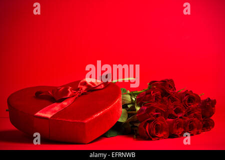 Un San Valentino scatola di caramelle e rose rosse su sfondo rosso Foto Stock