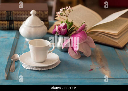 Una bella tazza di caffè e un libro aperto su un tavolo di legno Foto Stock