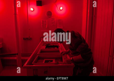 Un uomo si sviluppa le fotografie in una camera oscura. Foto Stock