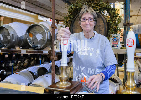 Una donna tira una pinta di birra in un CAMRA real ale festival. Foto Stock