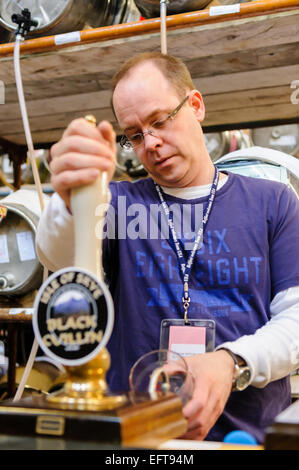 Un uomo tira una pinta di birra in un CAMRA real ale festival. Foto Stock