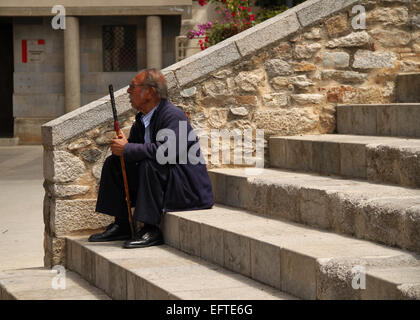 Uomo vecchio con bastone da passeggio seduta su passi nella città vecchia di Girona (Gerona), Catalogna, Spagna Foto Stock