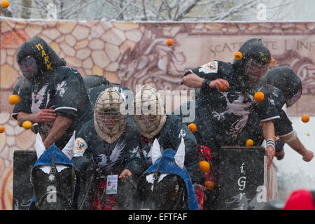 Tubi espulsori arancione combattimenti da un carrello durante una nevicata come parte della "battaglia delle Arance" al Carnevale di Ivrea. Foto Stock