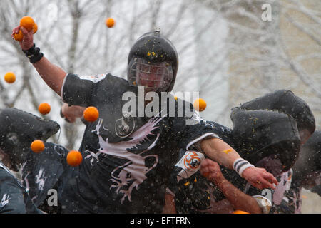 Un degli aranceri combattimenti da un carrello durante una nevicata come parte della "battaglia delle Arance" al Carnevale di Ivrea. Foto Stock