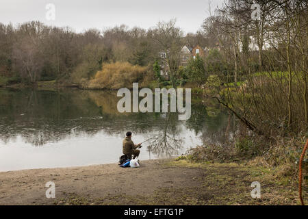 Un lone fisher-uomo che cerca la sua fortuna nella Valle della Salute stagno su una domenica di gennaio Foto Stock