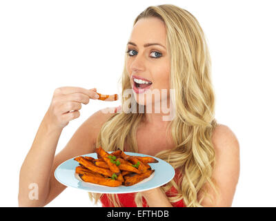 Fiducioso felice giovane donna di mangiare pane appena sfornato o arrosto di patata dolce chip isolati contro uno sfondo bianco con un tracciato di ritaglio e spazio di copia Foto Stock