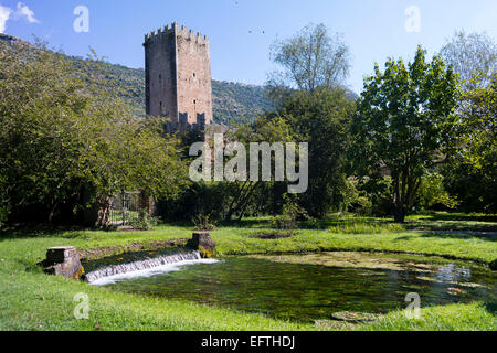 La torre del palazzo baronale e una cascata di acqua nel Giardino di Ninfa. Italia Foto Stock