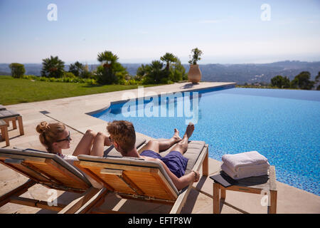 Coppia in vacanza al sole su una sedia a sdraio da una piscina della villa guardando oltre la Cote d'Azur Foto Stock