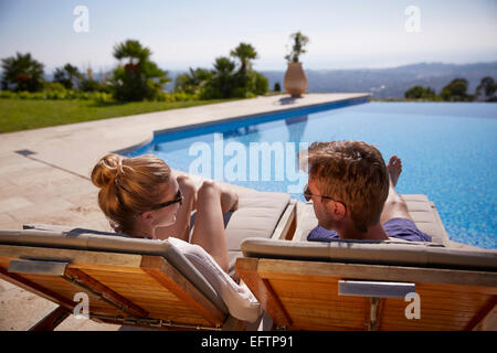 Coppia in vacanza al sole su una sedia a sdraio da una piscina della villa guardando oltre la Cote d'Azur Foto Stock