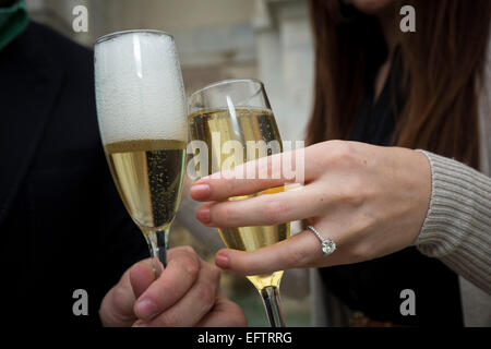 Anello di fidanzamento a portata di mano durante la tostatura con vino frizzante. Foto Stock