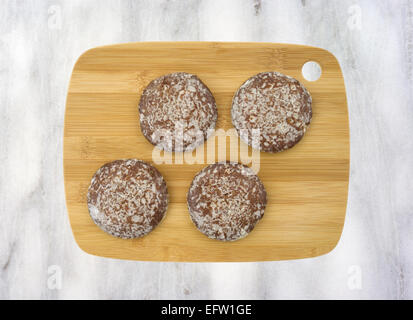 Vista dall'alto di diversi vetri gingerbread cookie su un legno tagliere in cima a un banco di marmo alto. Foto Stock