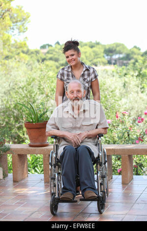 Senior uomo essendo spinto in carrozzella Foto Stock