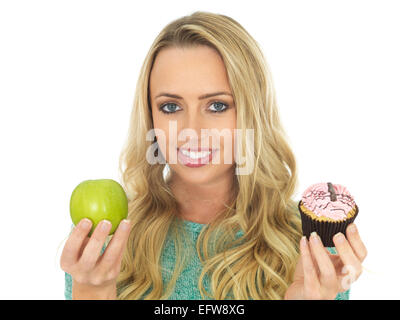Giovane donna holding e confrontando la torta e frutta Foto Stock