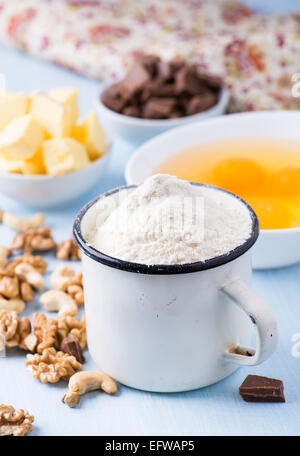 Tazza di farina, uova, burro, dadi e aggiungete pezzetti di cioccolato. Ingredienti per la cottura. Messa a fuoco selettiva Foto Stock