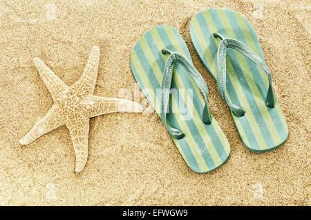 Ciabatte infradito ciabatte sulla spiaggia di sabbia di stelle marine estate vacanze la nozione di spazio di copia digitale filtri sbiadito retro vintage Foto Stock