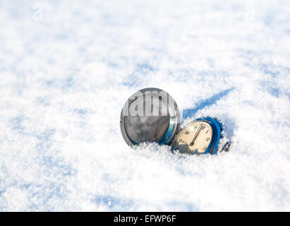 Orologio antico giaceva su un sfondo innevato Foto Stock