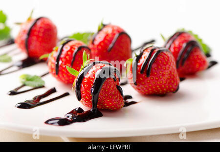 Fragole fresche in salsa di cioccolato sulla piastra bianca. Messa a fuoco selettiva Foto Stock